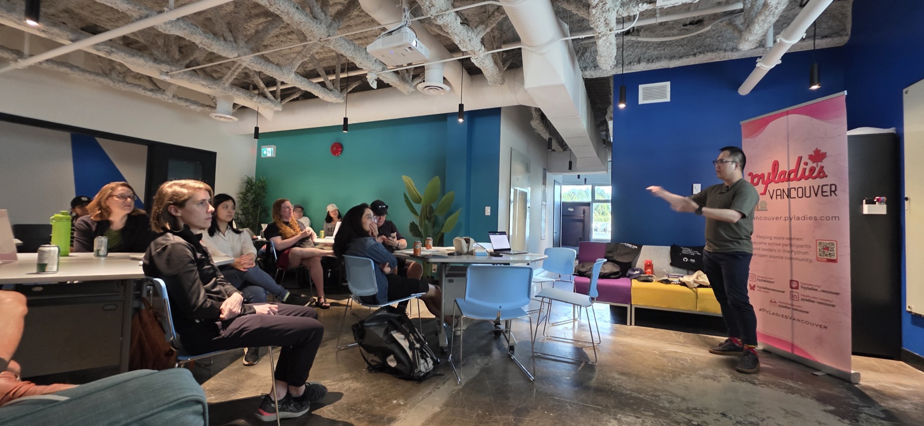 Daniel Chen gesturing while presenting next to the PyLadies Vancouver banner